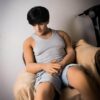 Rowan lying naked on bed in dim light