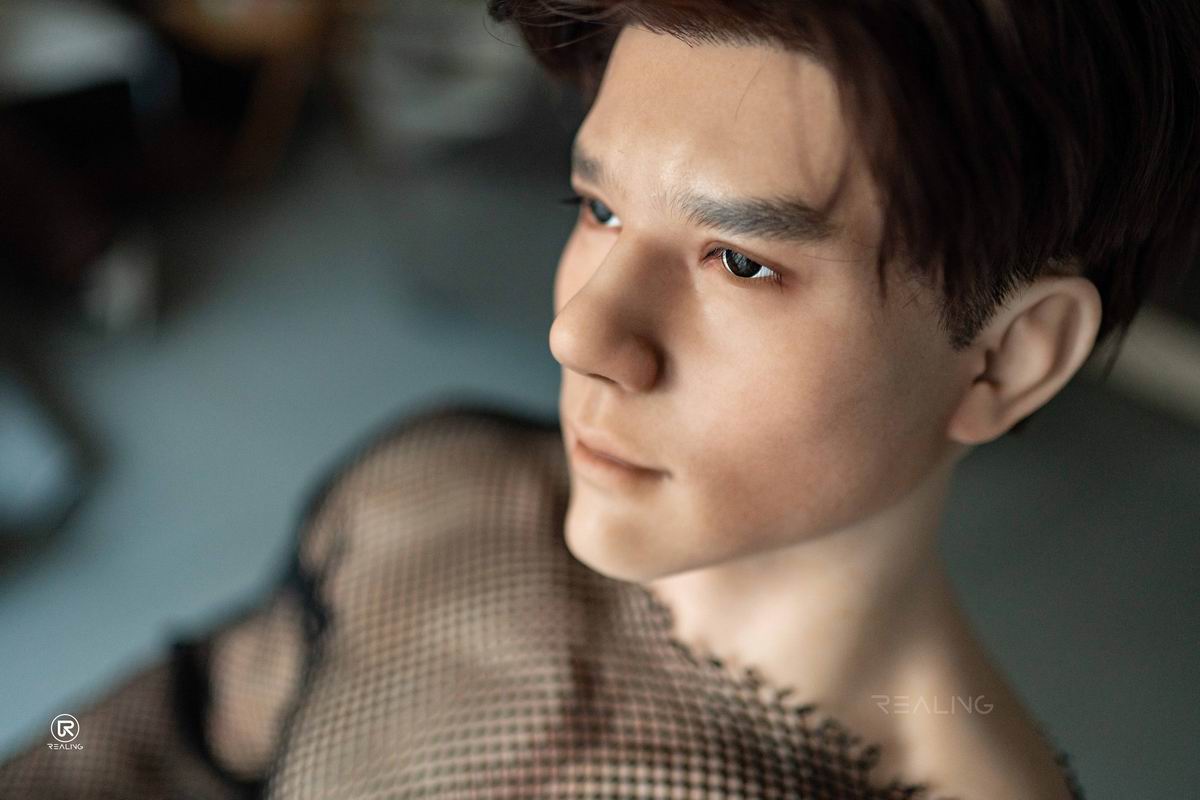 Realistic male doll placed on a cozy bed at night