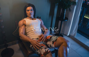 gay man sitting alone at laptop with male doll beside him