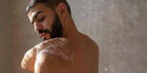Rinsing a male torso doll with lukewarm water in the shower.